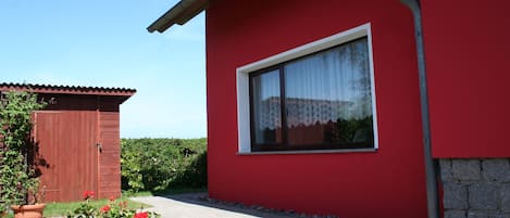 A red building with a window, a door, and a paved path.