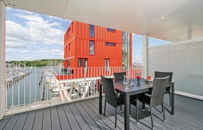 A balcony with a table and chairs, overlooking a marina with boats and a red building. - Priwallpromenade 27, Whg 6 (Travemünde Waterfront)