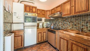A kitchen with wooden cabinets, a refrigerator, a microwave, a stove, and a tiled backsplash. - Stunning home in Les Moutiers En Retz (Les Moutiers En Retz)