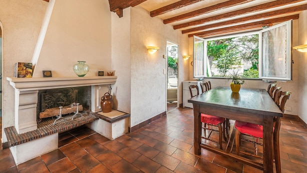 A rustic dining area with a wooden table and chairs, a fireplace with decorative items, and a view through a window. - Stunning home in Les Moutiers En Retz (Les Moutiers En Retz)