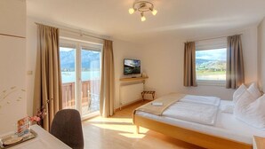 Een hotelkamer met een bed, een bureau, een stoel, een televisie en uitzicht op het groen.