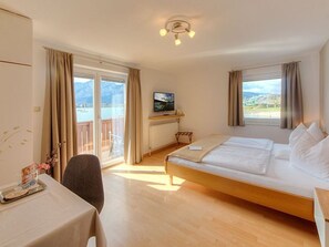 Ein Hotelzimmer mit Bett, Schreibtisch, Stuhl, Fernseher und Blick ins Freie.