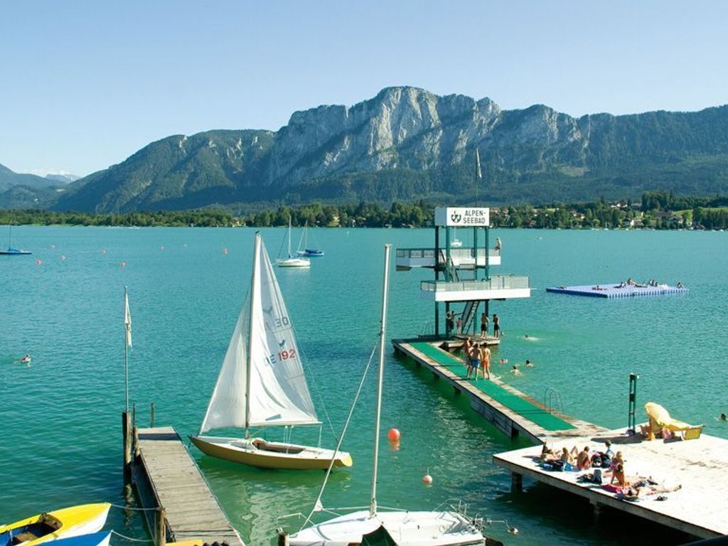 Ein See mit Booten, einem Steg und einem Rettungsturm.