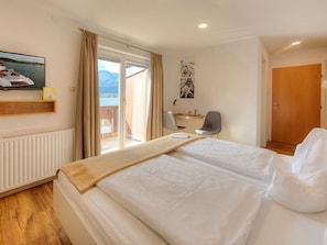 Une chambre d’hôtel avec un lit, un bureau, une chaise, une fenêtre donnant sur un paysage agréable et une porte.