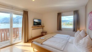 Een slaapkamer met een bed, een televisie, uitzicht op zee en een balkon.