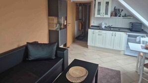 A compact living space with a sofa, a small table, a kitchenette, and a dining area. - Holiday apartment on Blankensee (Trebbin)