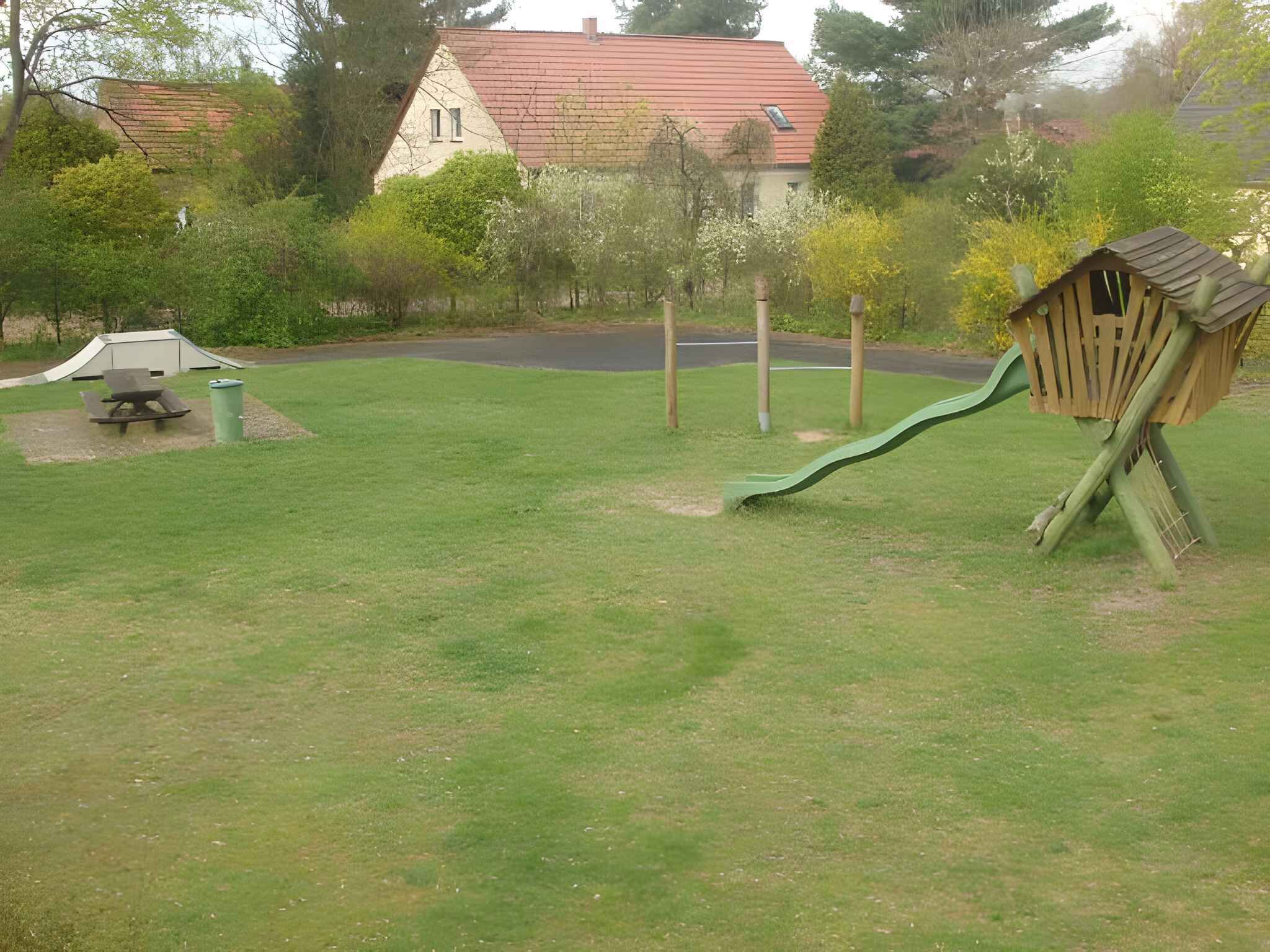 A grassy outdoor area with a play structure, a picnic table, and a small shed.