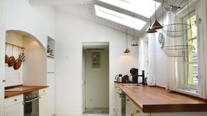 A kitchen with white cabinets, a wooden countertop, and pendant lighting. - 2 bedroom amazing home in Gilleleje (Gilleleje)