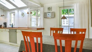A kitchen with a dining area, featuring a wooden table and chairs, a window with curtains, and a clock on the wall. - 2 bedroom amazing home in Gilleleje (Gilleleje)