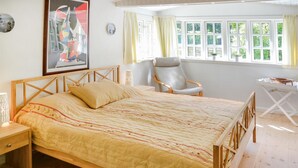 A bedroom with a wooden bed, a chair, a small table, and a window with curtains. - 2 bedroom amazing home in Gilleleje (Gilleleje)