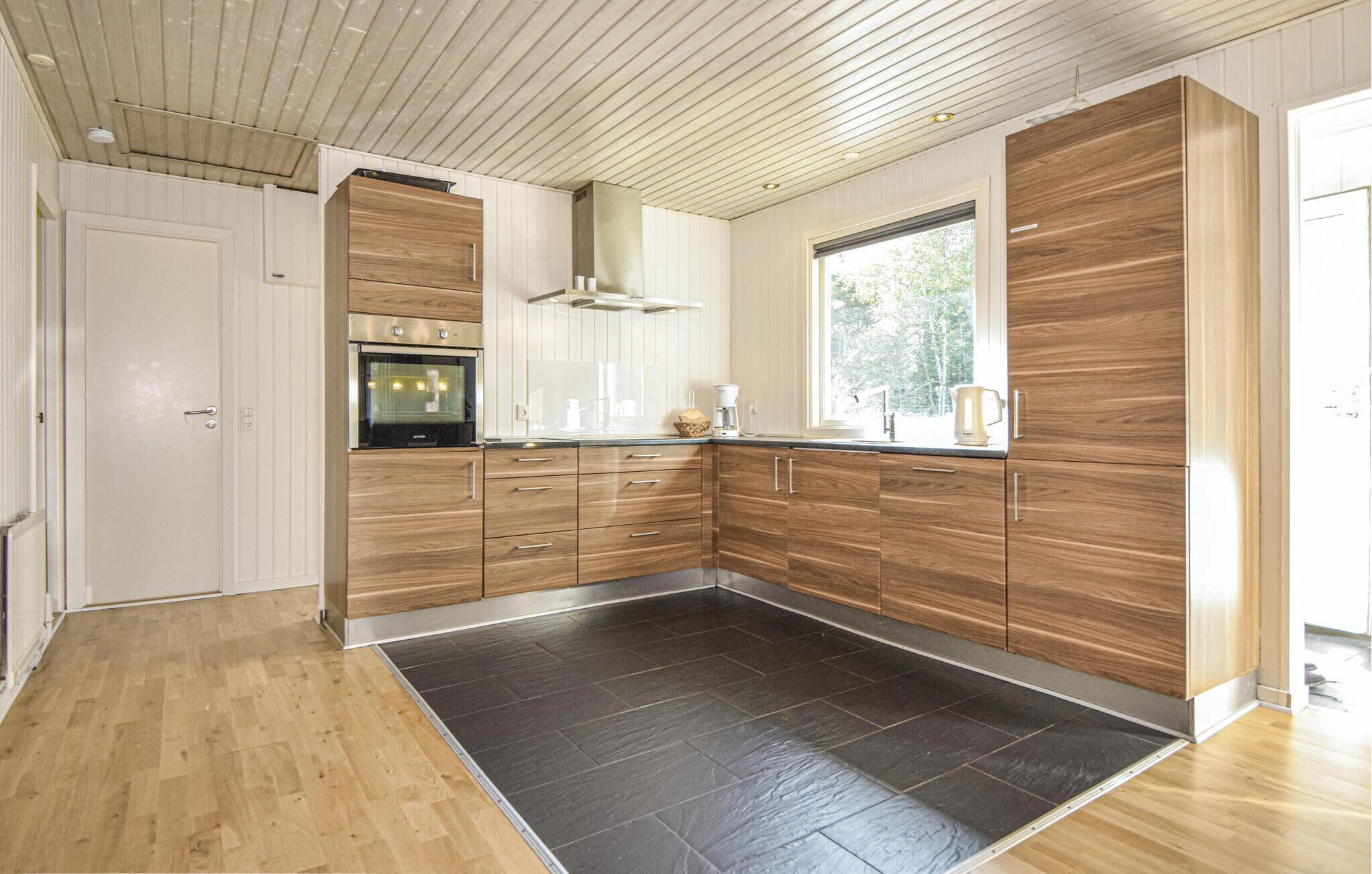 Una cucina moderna con mobili in legno, forno integrato e un'ampia finestra che offre luce naturale.