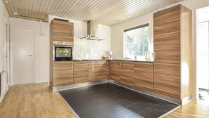 Una cocina moderna con armarios de madera, horno empotrado y un amplio ventanal que proporciona luz natural.