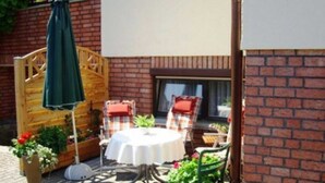 An outdoor patio with a round table, two chairs, a wooden fence, and potted plants. - FeWo Weber - GM 69911 - FeWo Weber (Graal-Müritz)