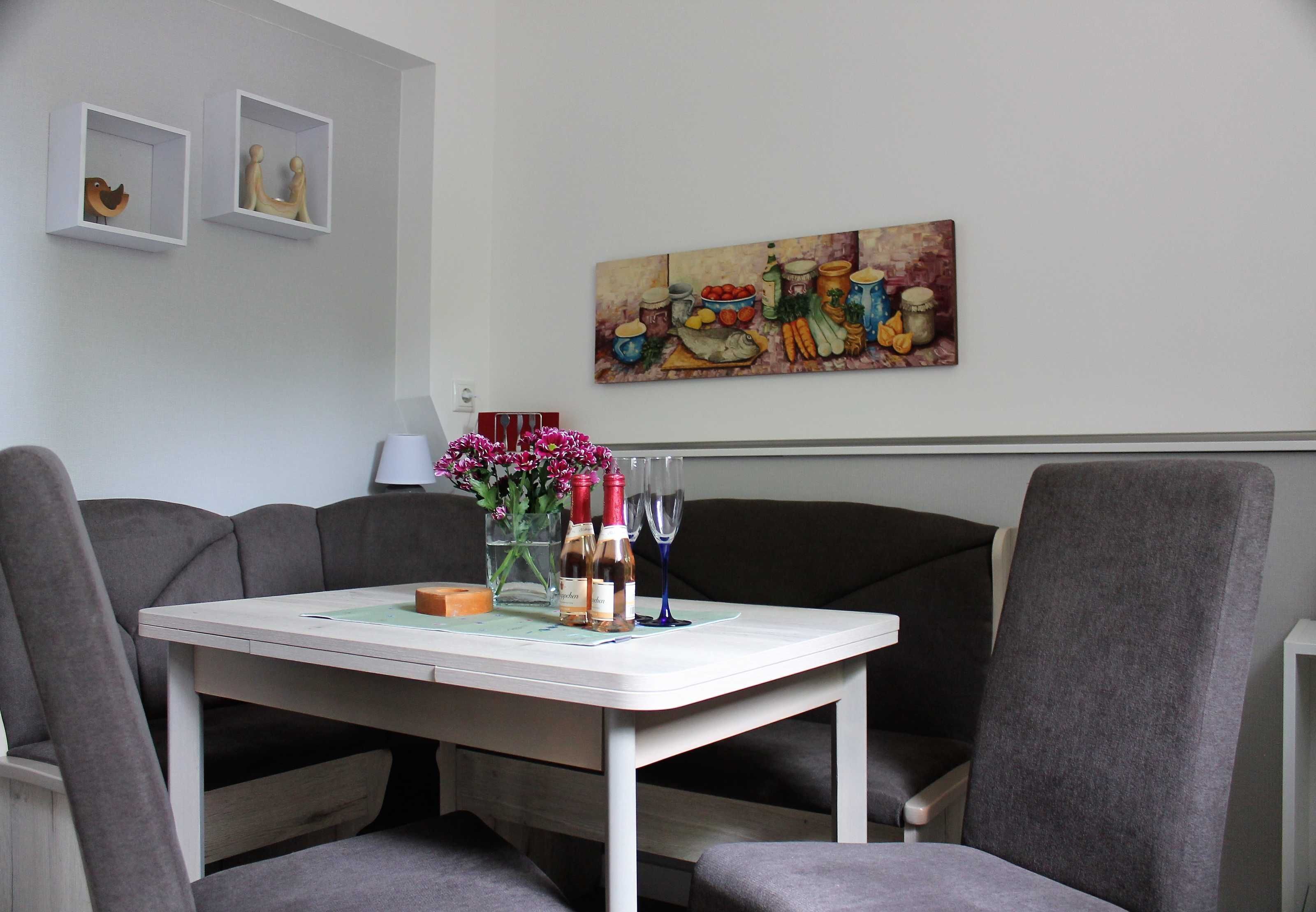 Ein Essbereich mit Tisch, Stühlen und einem Bild an der Wand.
