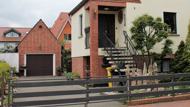 A residential building with a brick facade, a garage, and a staircase leading to the entrance. - FeWo Weber - GM 69911 - FeWo Weber (Graal-Müritz)