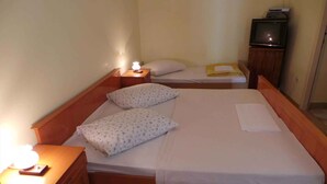 Ein Einzelbett mit zwei Kissen, ein Nachttisch mit Lampe und ein Fernseher auf einem Schrank.