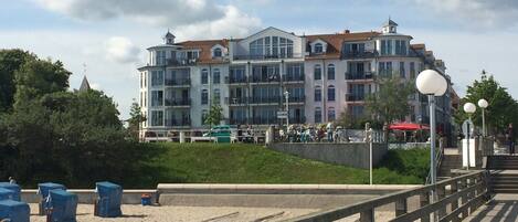 A waterfront hotel with multiple balconies, a beach area, and a promenade.