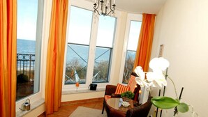 A room with a view of the sea, a chandelier, wicker furniture, and a potted plant. - (60) 3-room apartment with balcony - direct lake view - apartment house (Kühlungsborn)