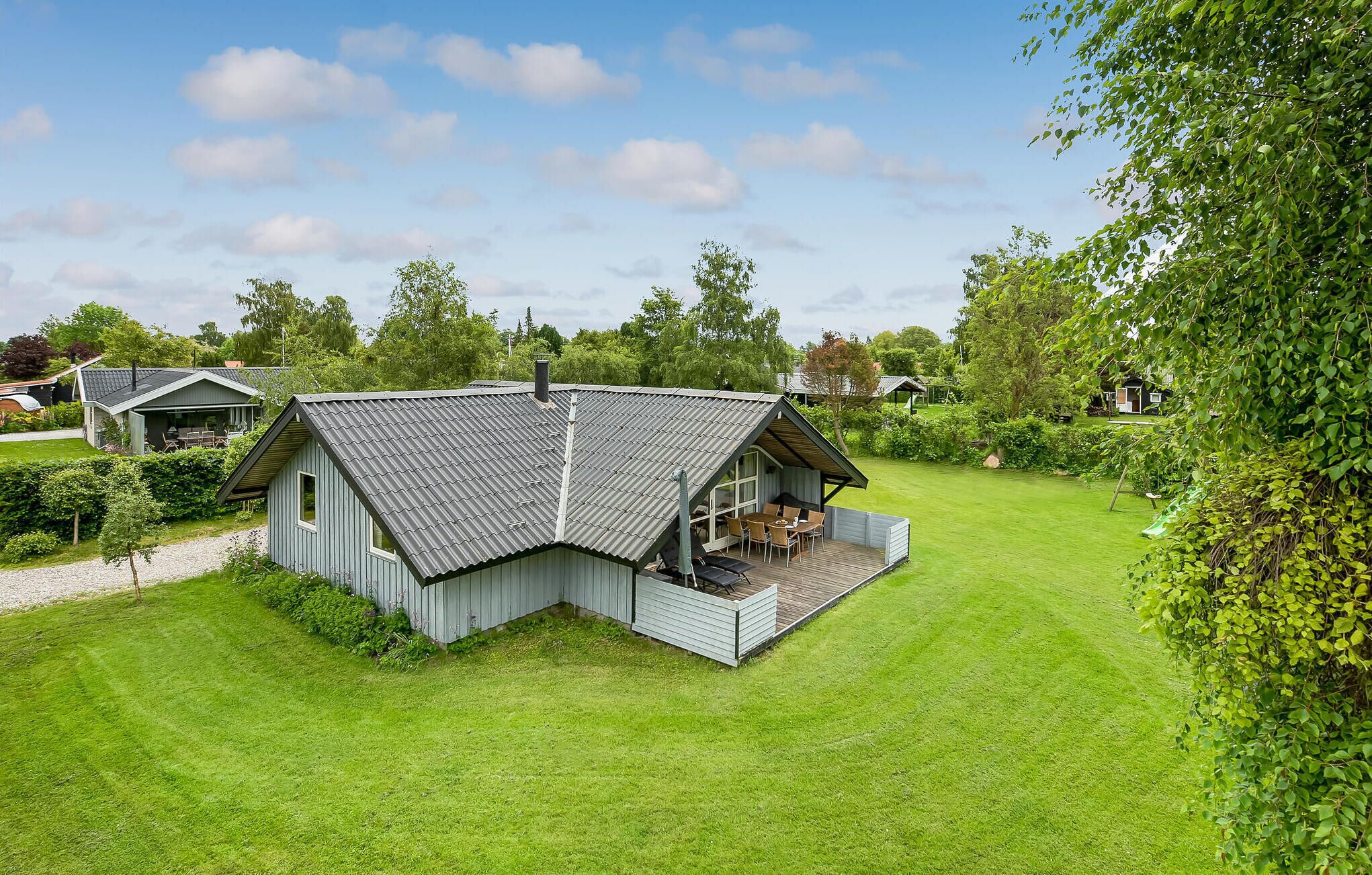 A single-story house with a sloped roof, a covered porch with seating, and a well-maintained lawn.