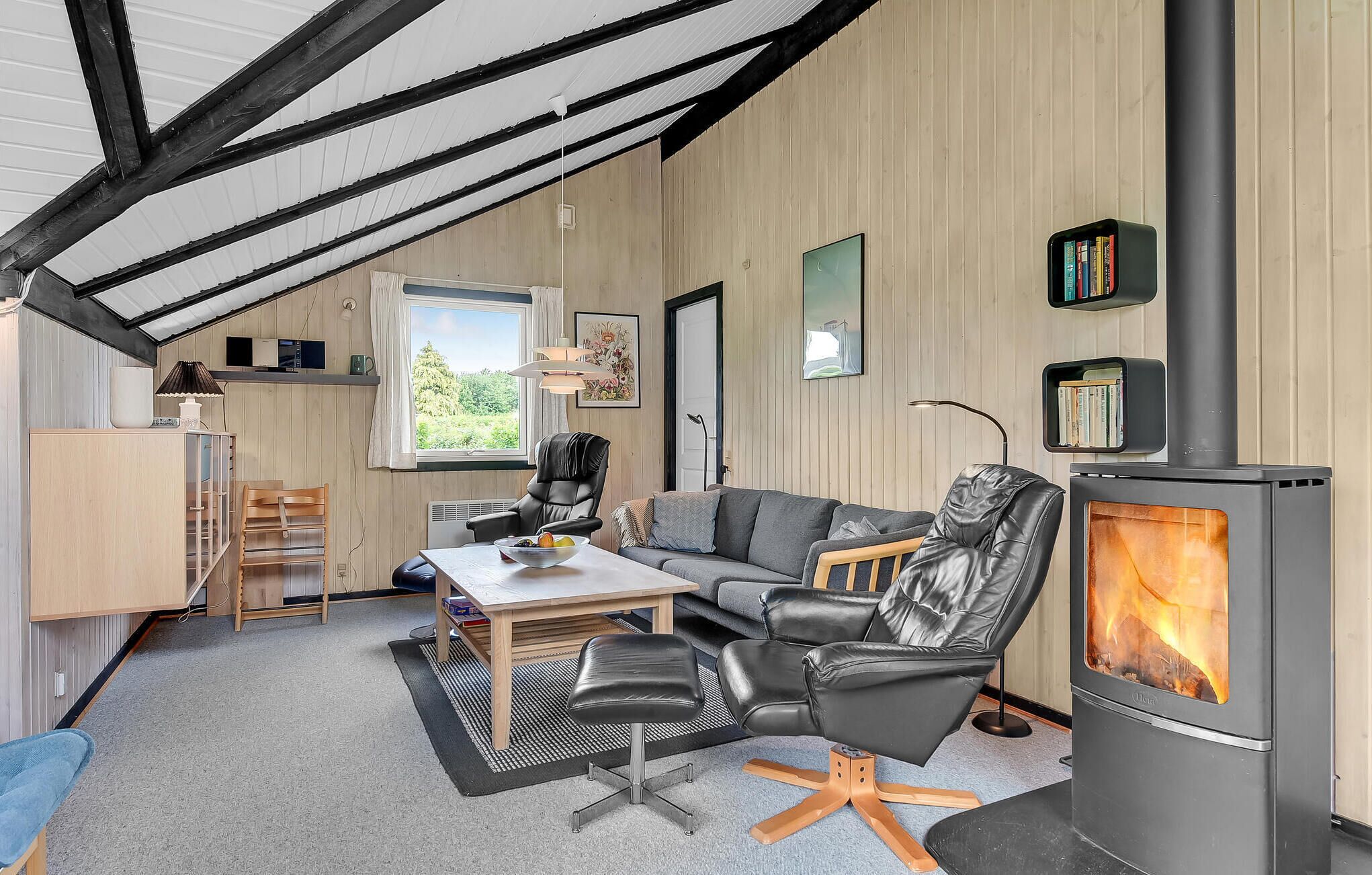 A cozy living room with a fireplace, a sofa, a dining table, and a bookshelf.
