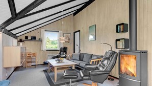 Tunnelmallinen olohuone, jossa on takka, sohva, ruokapöytä ja kirjahylly.