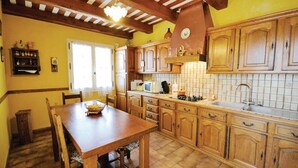A kitchen with wooden cabinets, a tiled backsplash, and a dining area with a table and chairs. - 3 bedroom amazing home in Lagnes (Lagnes)