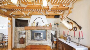 A rustic interior with a stone fireplace, wooden ceiling beams, and a mounted deer head. - 3 bedroom amazing home in Lagnes (Lagnes)