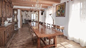 A spacious dining area with a long wooden table and chairs, a chandelier, and rustic decor including antlers and a clock. - 3 bedroom amazing home in Lagnes (Lagnes)