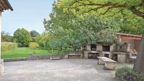 A stone patio with a fire pit, surrounded by stone walls and a large tree. - 3 bedroom amazing home in Lagnes (Lagnes)