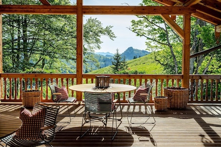 A wooden deck with a round table and chairs, overlooking a mountainous landscape.. Family room with 2 bedrooms Berghotel Sudelfeld - Berghotel Sudelfeld