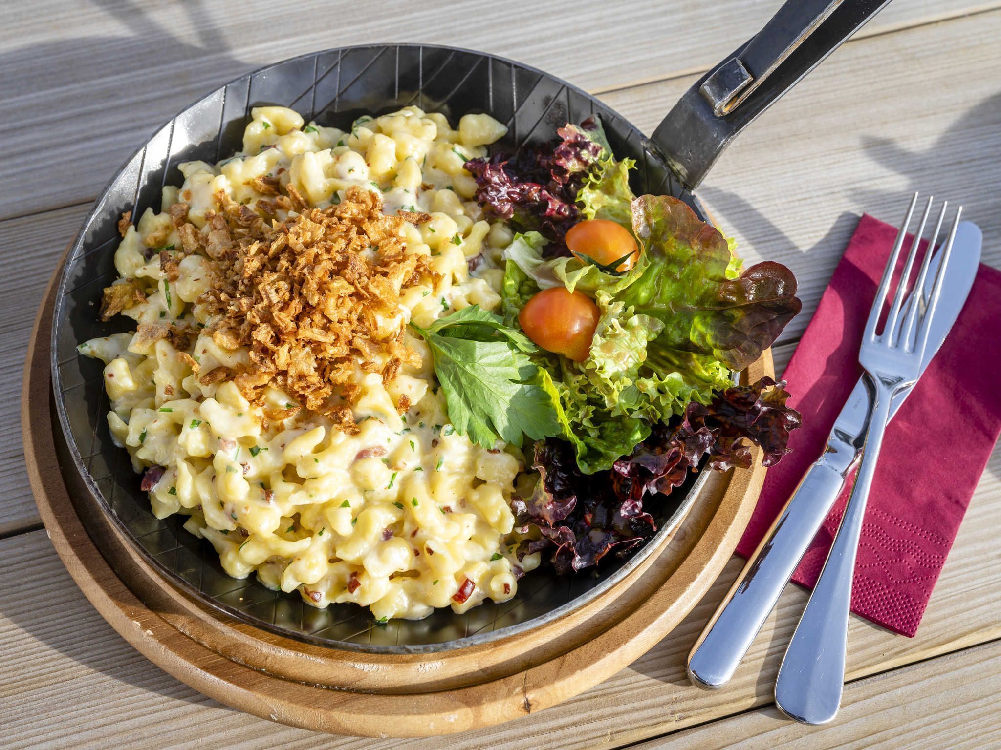 A meal with pasta, salad, and a fork on a wooden table.