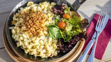A meal with pasta, salad, and a fork on a wooden table.