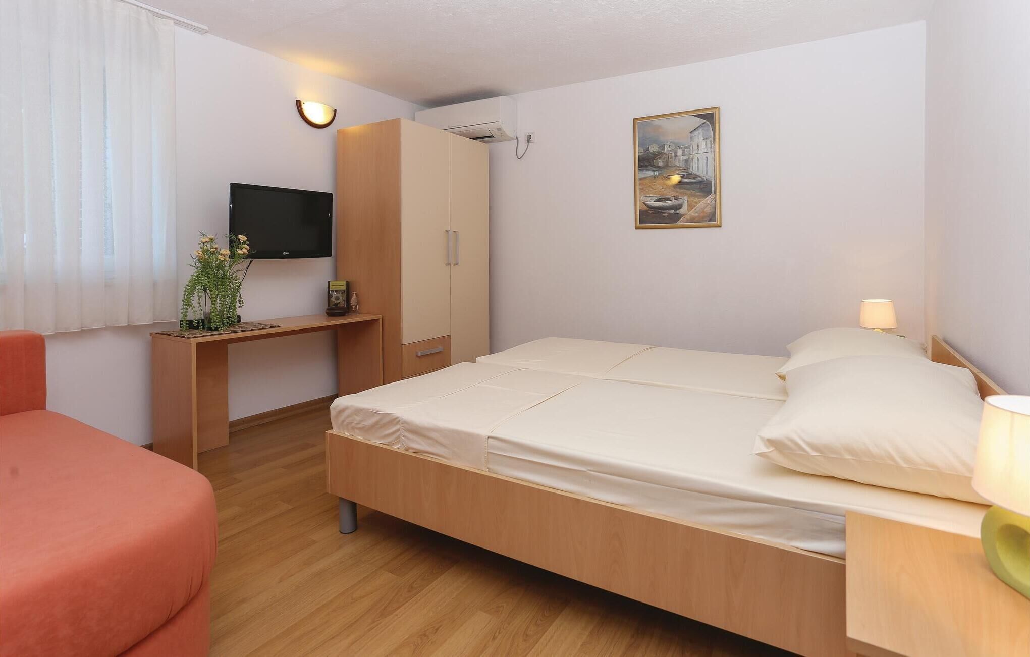 Habitación de hotel con una cama, un escritorio, un televisor y un cuadro en la pared.