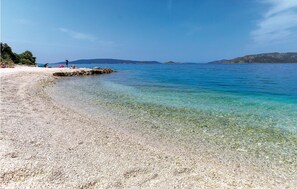 A pebble beach with clear water and distant mountains. - Lovely home in Okrug Donji (Okrug Donji)