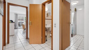 Habitación de hotel con balcón, baño con lavabo e inodoro, y zona de comedor con mesa y sillas.