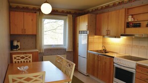 A compact kitchen with wooden cabinets, a refrigerator, a stove, and a dining table with chairs. - Nice home in Lenhovda with WiFi (Lenhovda)