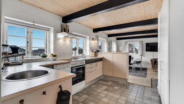 Une cuisine moderne dotée d’un grand îlot central, d’appareils électroménagers intégrés et offrant une vue sur l’extérieur.