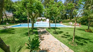A swimming pool surrounded by lush greenery and a stone pathway.