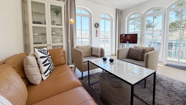 Een woonkamer met een bank, stoelen, een salontafel en een kast.