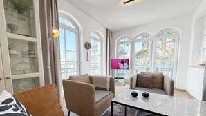 Een moderne woonkamer met een bank, fauteuils, een salontafel en een televisie.