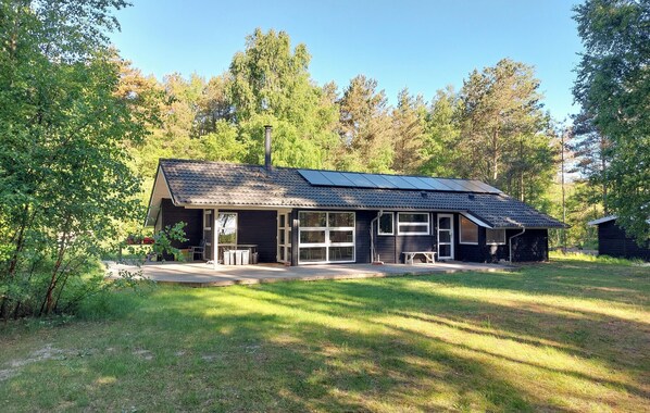A cabin with a sloped roof, large windows, and a covered porch area.