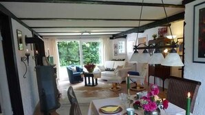 A dining area with a table set for four, surrounded by chairs, and a view of the garden through the open door. - Marc Chagall apartment - Rosengut Falkenstein (Braderup)