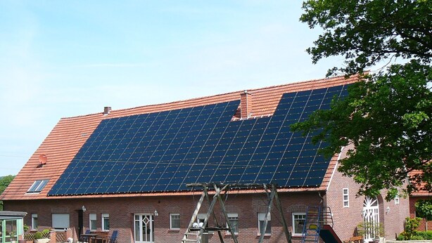 A building with a red-tiled roof and a large solar panel array.