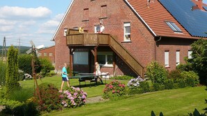 A red brick building with a sloped roof, a wooden deck, and a solar panel installation.