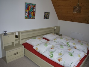 Un dormitorio con una cama, una mesita de noche, una cómoda y dos cuadros colgados en la pared.