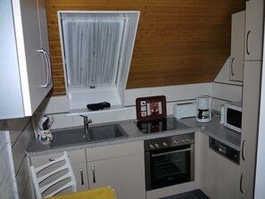 Una cocina compacta con lavaplatos, estufa, microondas y cafetera.
