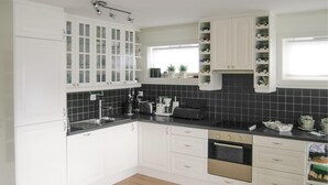 A modern kitchen with white cabinets, a black countertop, and a window providing natural light.