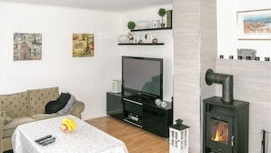 A living room with a TV, sofa, table with bananas, and a fireplace.