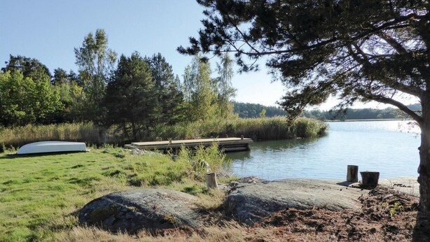 A lakeside setting with a dock, a boat, and a grassy area. - Beautiful home in Trosa (Trosa)