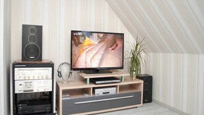 A home theater setup with a flat-screen TV, a soundbar, and a vintage stereo system. - Apartment Lischewski - Volker Lischewski (Steinberg)